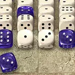 Useita valkoisia ja sinisiä noppia rivissä kivisellä pinnalla